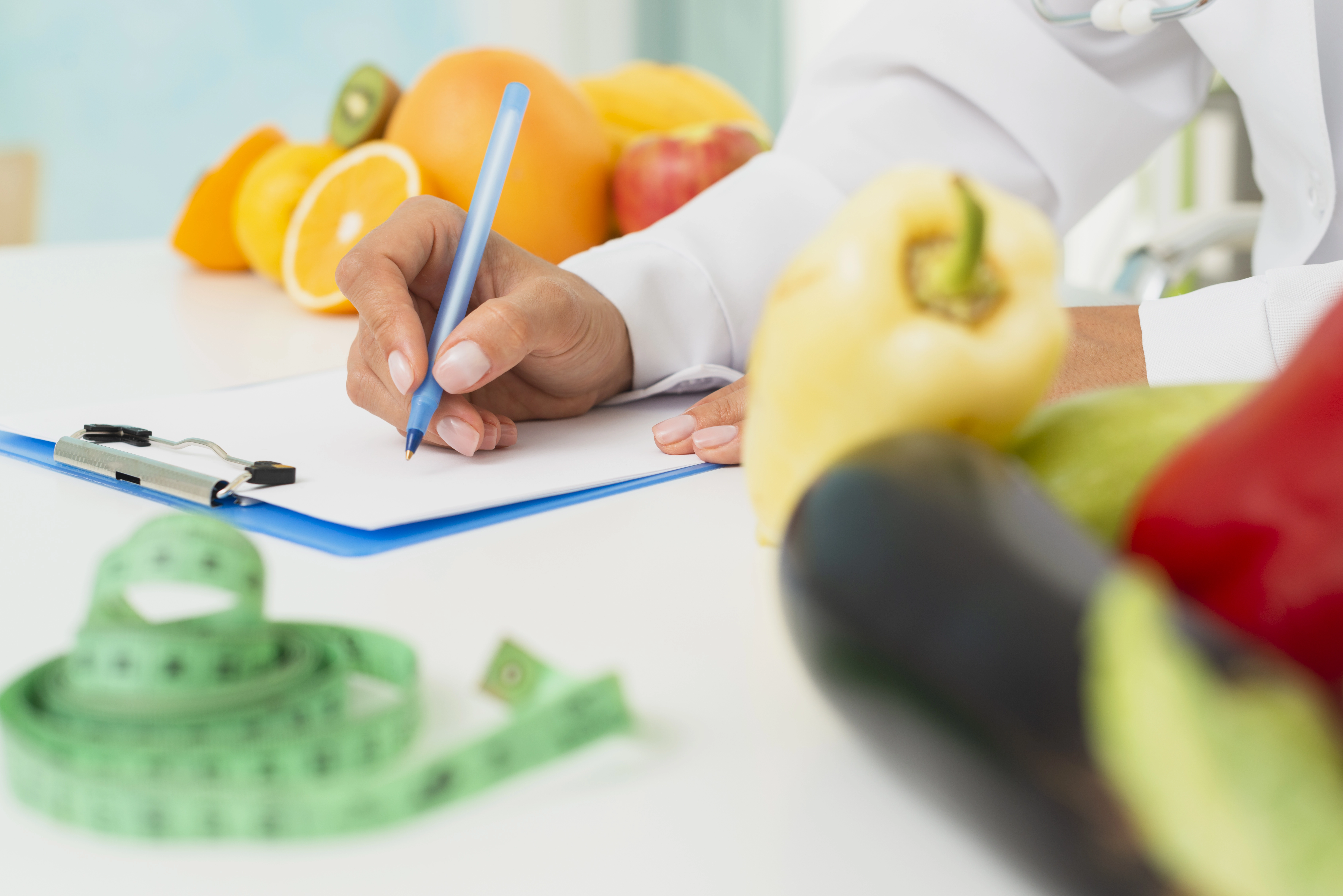 Professionnel de santé rédigeant une ordonnance nutritionnelle, avec des légumes et fruits.
